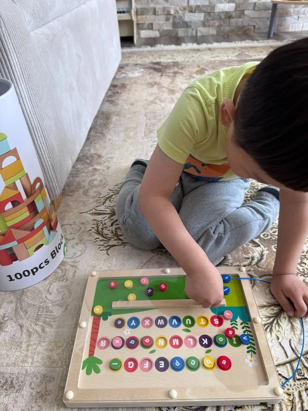 Preschooler playing with magnetic alphabet maze to learn letters through play at Kido Heaven Child Care
