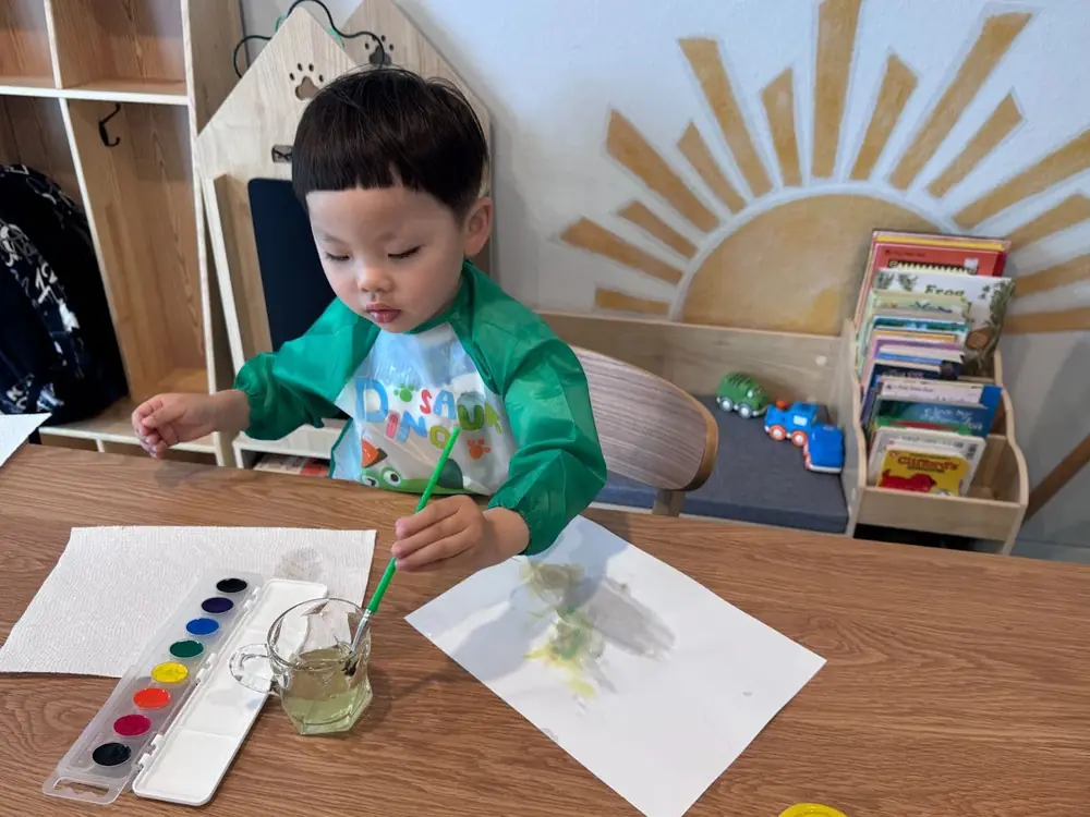 Child painting with watercolor in calm environment
