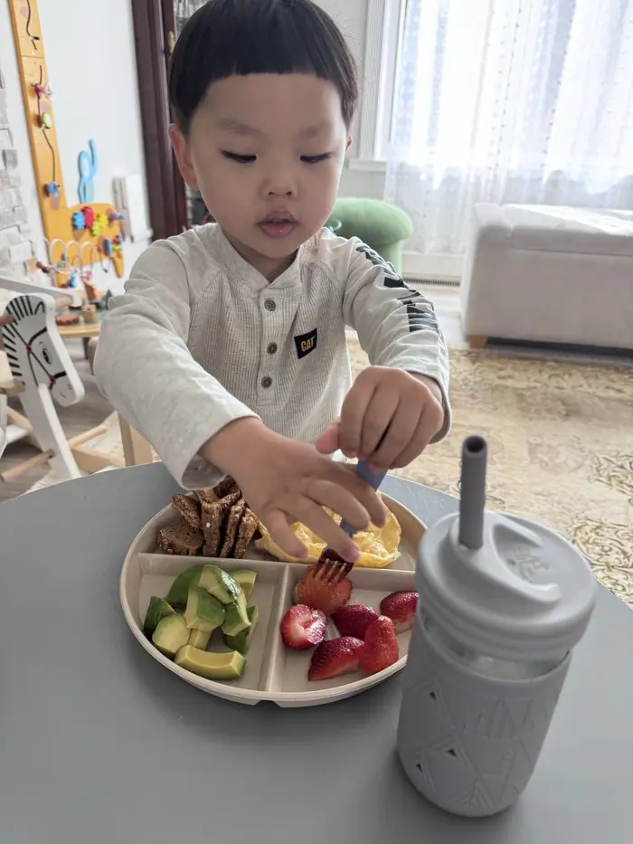Toddler eating independently with a spoon – "Child developing fine motor skills during mealtime
