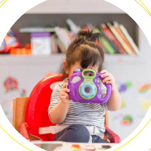 A toddler peeking through a toy camera