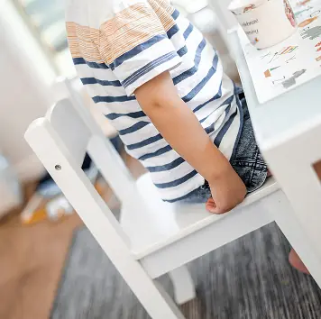 A child climbing onto a white chair