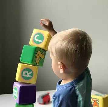 A toddler stacking soft letter blocks