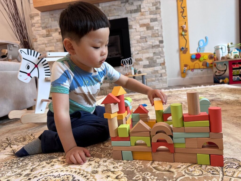 Preschooler using Montessori wooden blocks to explore shapes at Kido Heaven Child Care in Bothell, WA, fostering critical thinking skills.