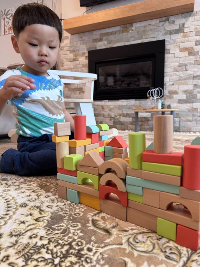 Toddler stacking Montessori cylinders in a nurturing classroom at Kido Heaven Child Care in Bothell, WA, enhancing hand-eye coordination and independence.