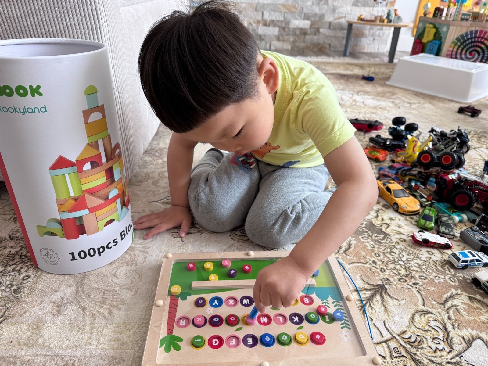 Child playing with a colorful magnetic alphabet maze board on a soft rug at Kido Heaven Childcare, promoting hands-on early learning through sensory play in Bothell, WA.