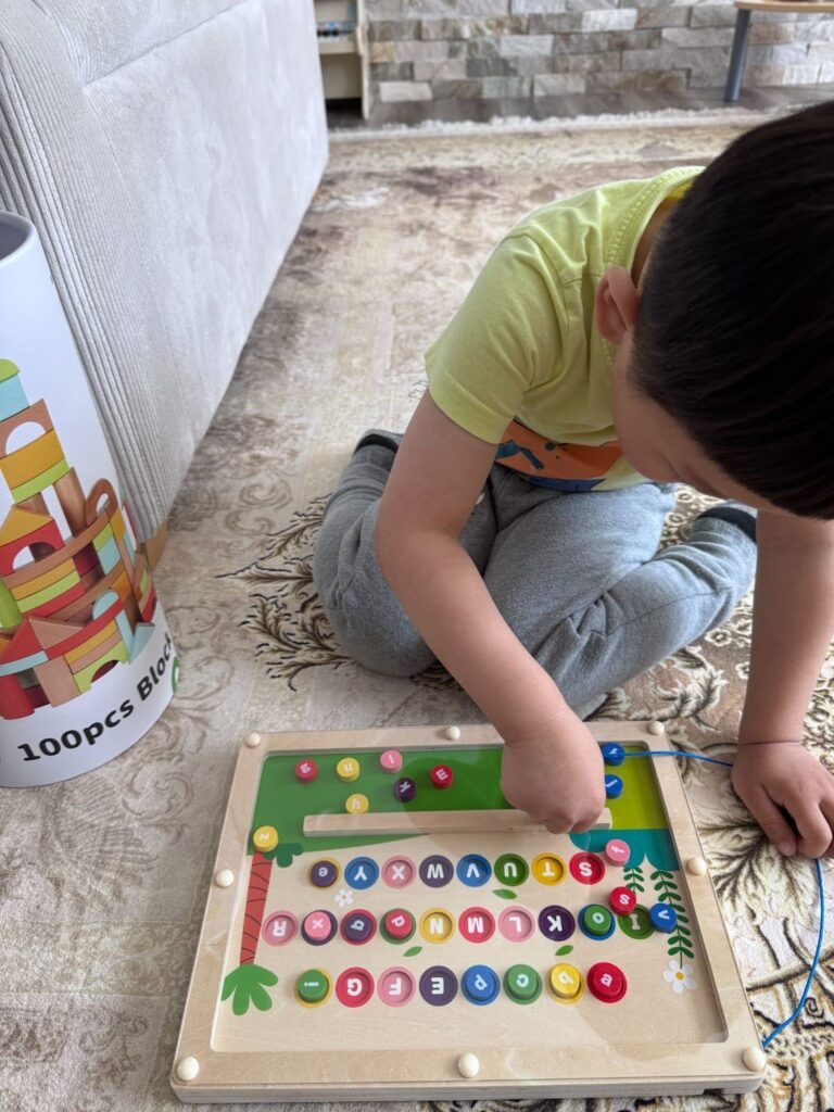 Preschooler playing with magnetic alphabet maze to learn letters through play at Kido Heaven Child Care