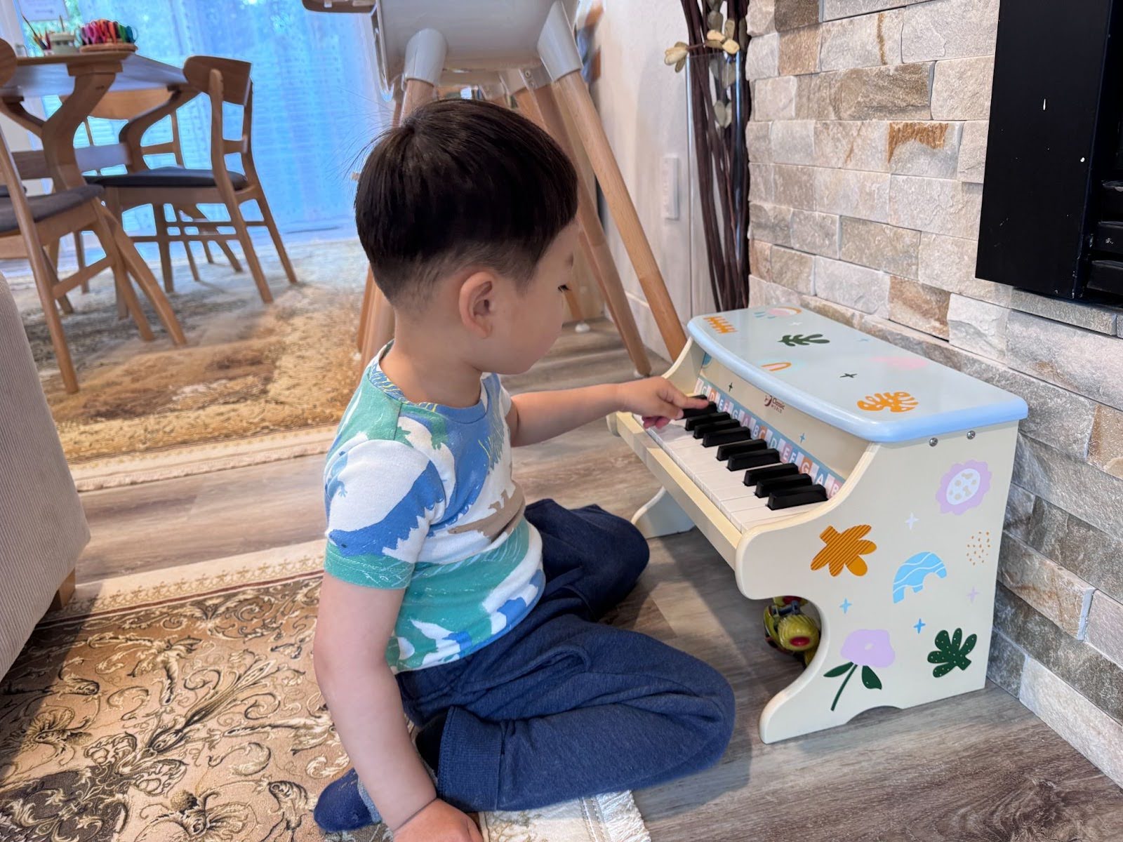 Child seated at a white toy piano with painted flowers, exploring music through hands-on play at Kido Heaven Childcare in Bothell.