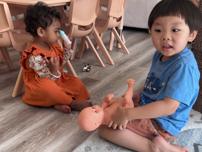 Children in pretend play with toys at daycare.
