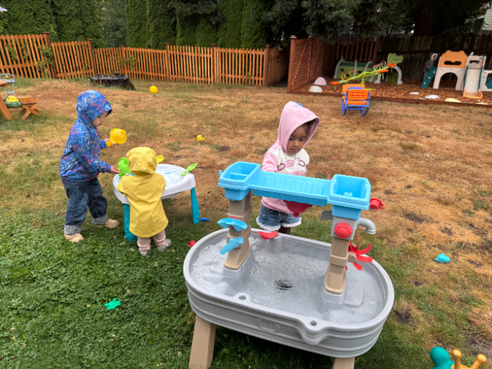 Happy toddlers playing in water table at summer camp