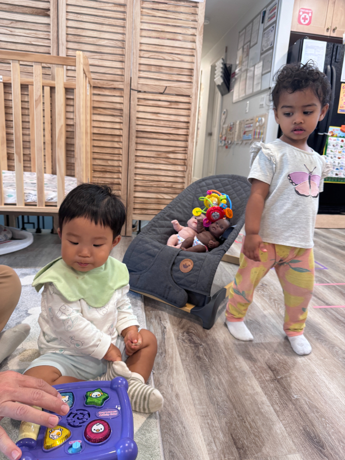 Bright and safe daycare classroom with colorful activity zones, low shelves, and soft play mats for young children