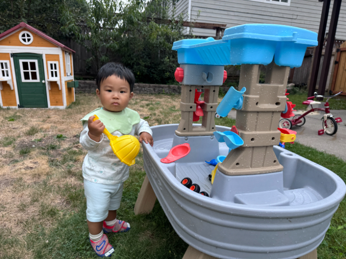 Toddler pouring water between containers for sensory development